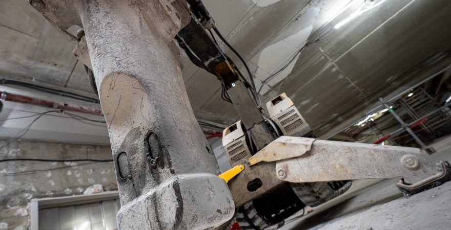 Robot de démolition équipé d’un marteau hydraulique intervenant sur un chantier intérieur SMB Bâtiment